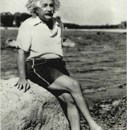 Man sitting on rock, wearing casual clothes.