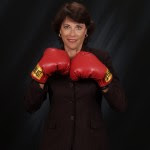 Woman wearing red boxing gloves, smiling confidently.