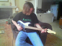 Person playing electric guitar on a couch.