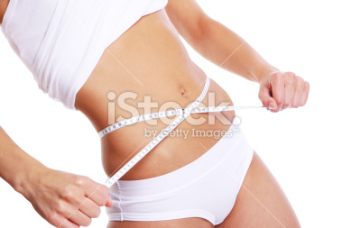 Woman measuring her waist with a tape measure, highlighting fitness.
